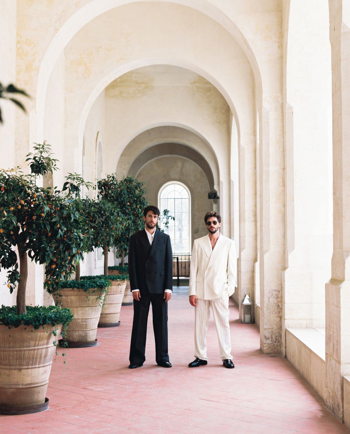 Two grooms in suits under stone arches